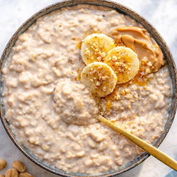 Bowl of peanut butter banana overnight oats on marble table near window soft morning light.