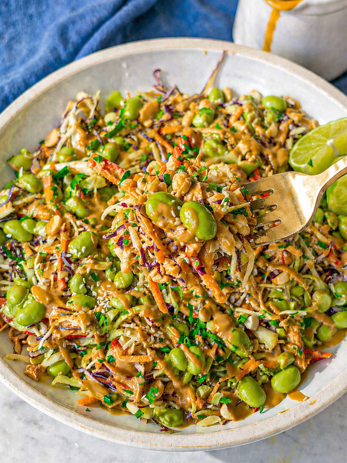 Close-up of cabbage salad with edamame and creamy peanut dressing, glossy and vibrant.
