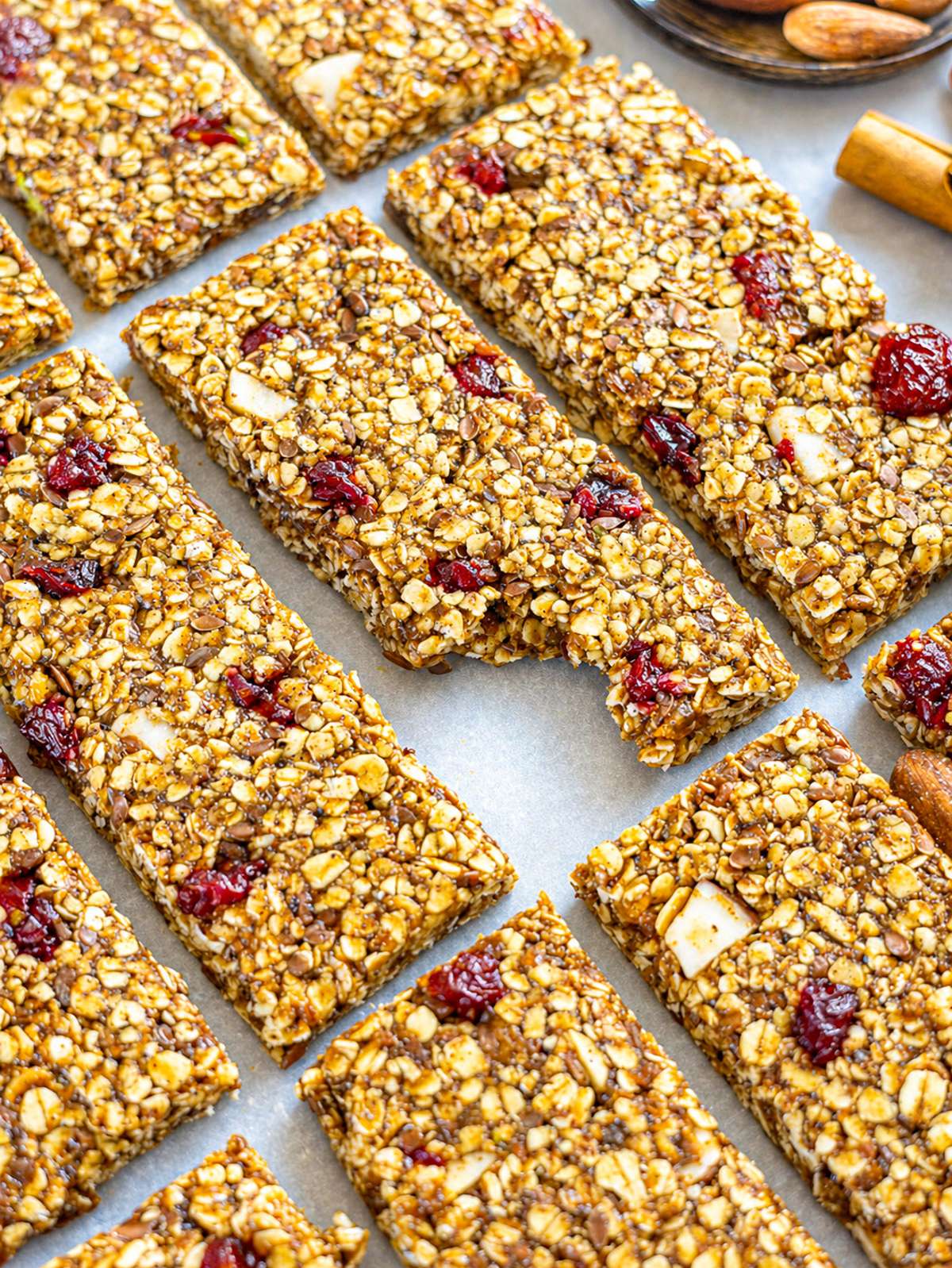 Close up of no bake oat bars with cranberries, seeds, and chopped nuts on marble.