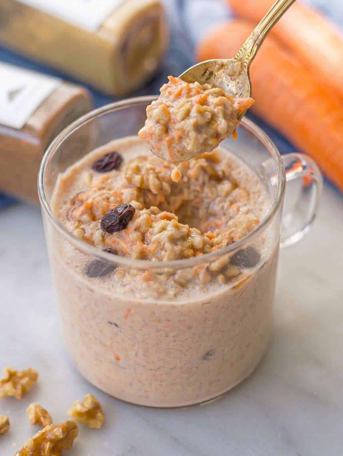 Creamy carrot cake overnight oats in jar with walnuts and cinnamon on marble table.