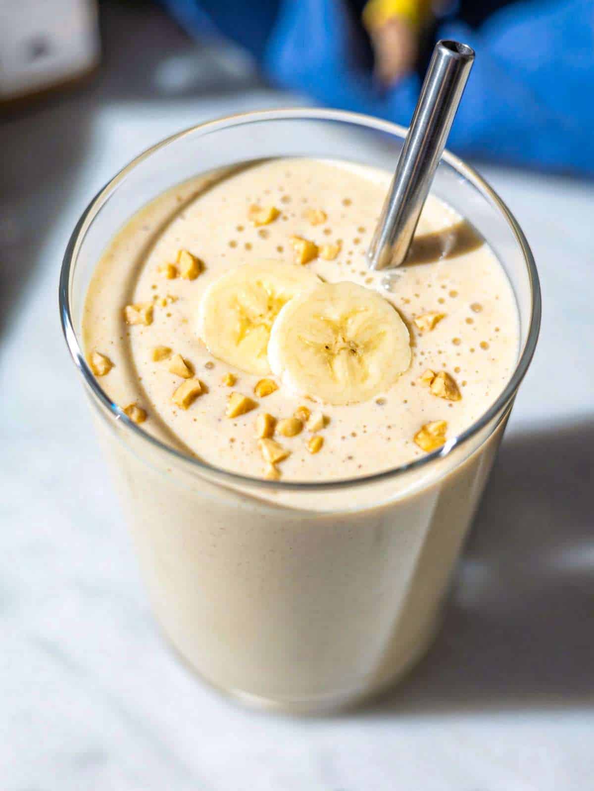 Creamy peanut butter banana smoothie in glass, bright and naturally lit.