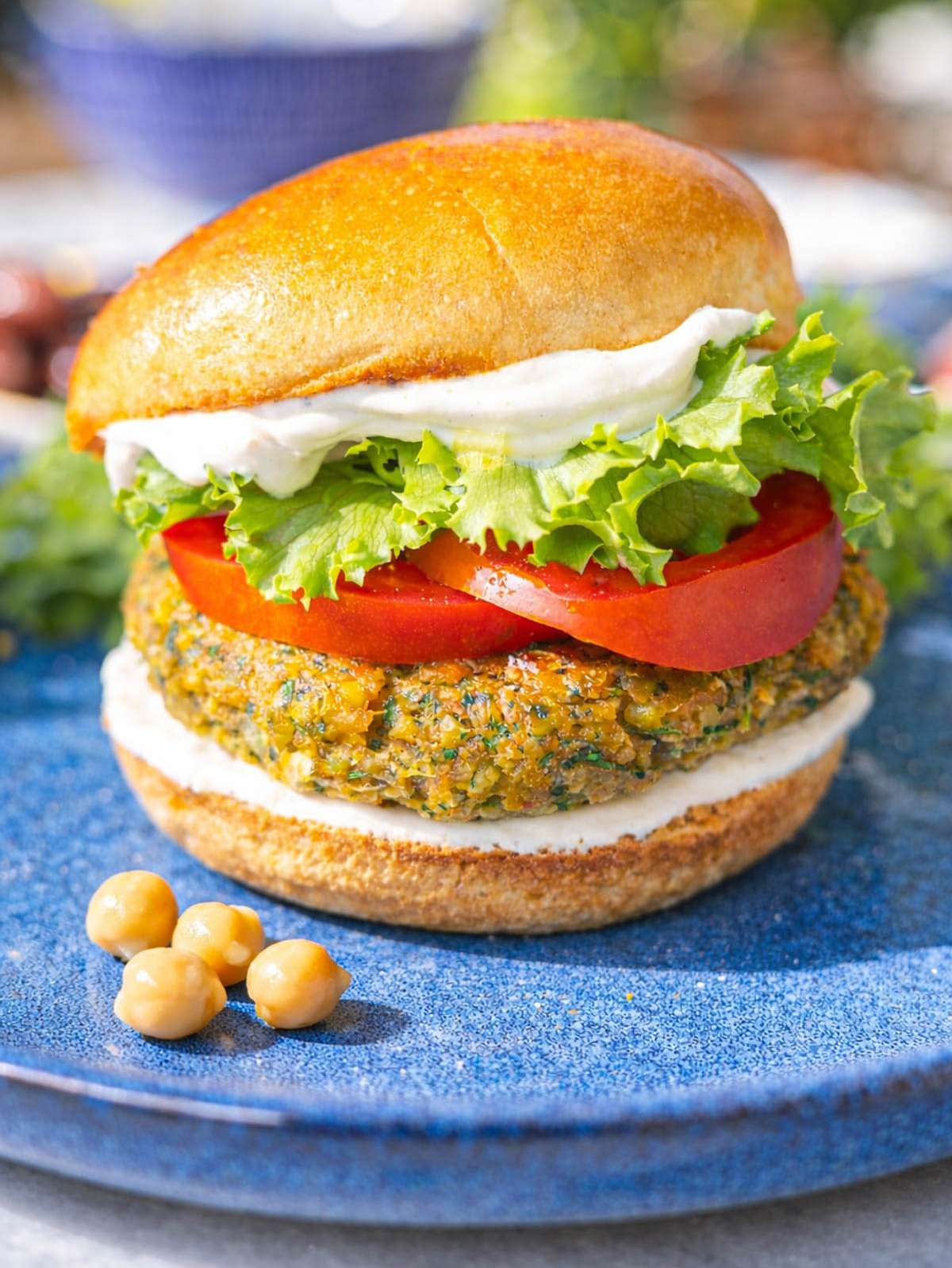 Falafel burger in bun with fresh toppings, golden crust visible on marble surface.