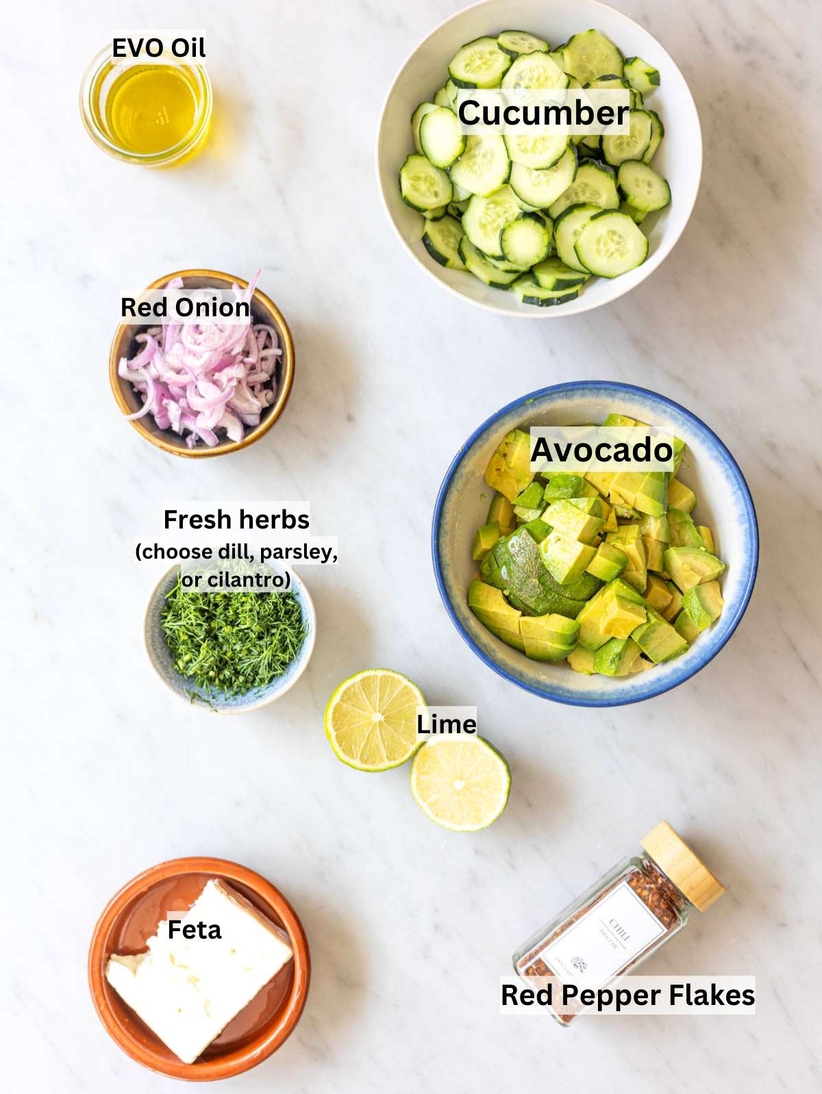 Fresh ingredients for cucumber avocado salad on marble table in natural window light.