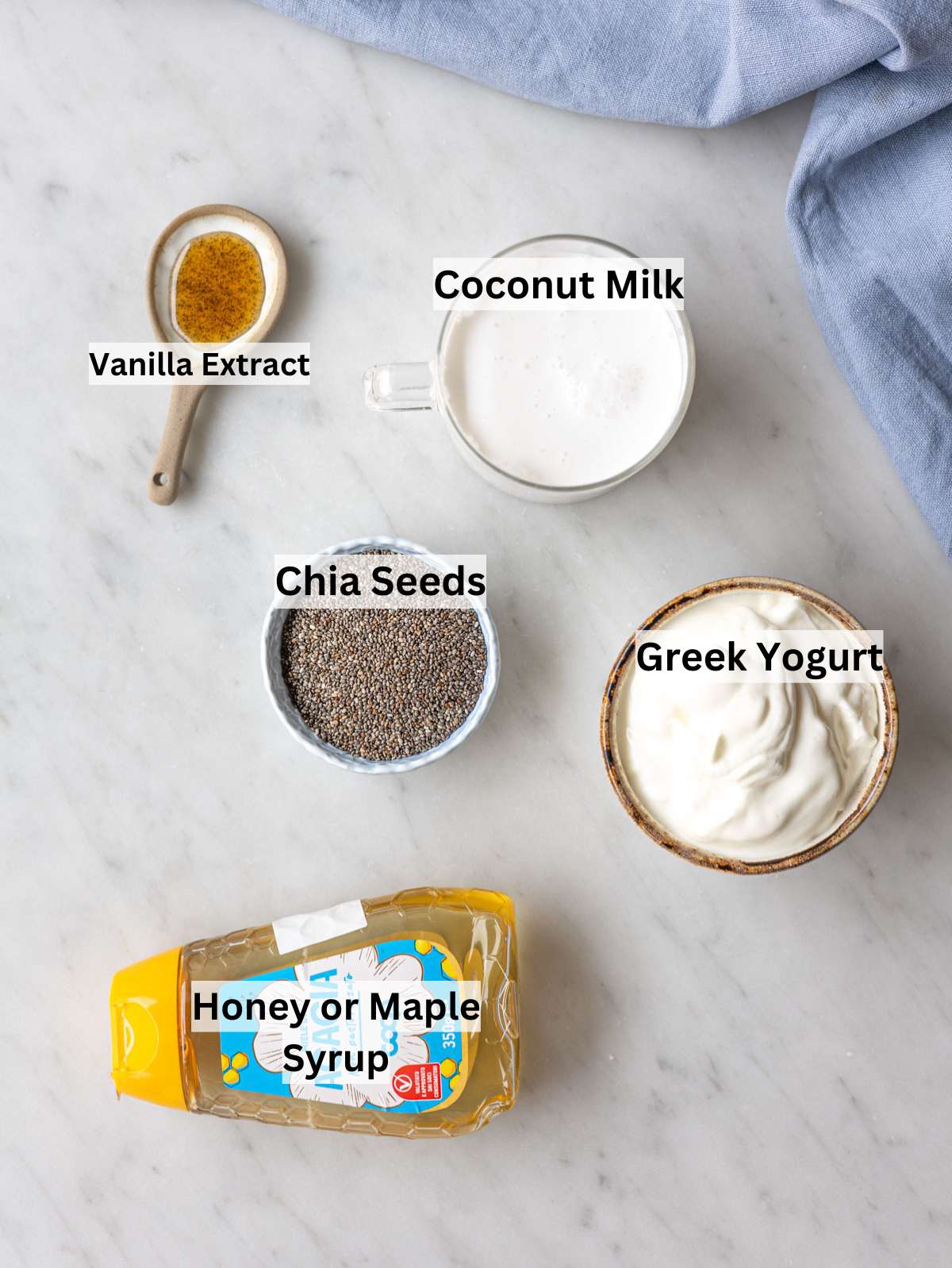 Ingredients for coconut chia pudding on marble table in soft natural window light.