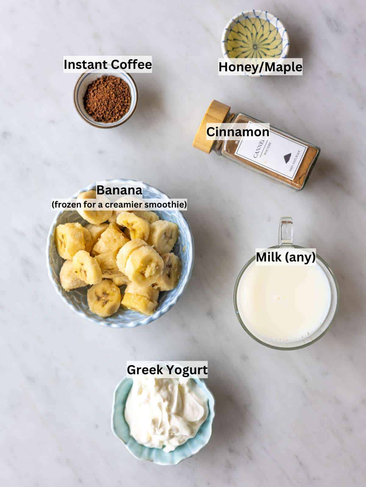 Ingredients for coffee smoothie on marble surface with bananas yogurt milk and coffee in natural light.