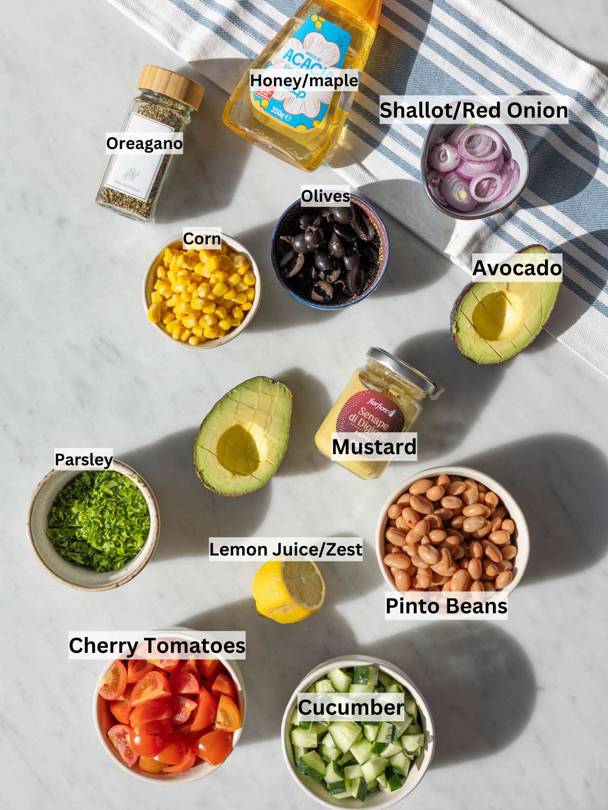 Ingredients for pinto bean salad on marble table with fresh vegetables and herbs in natural light.