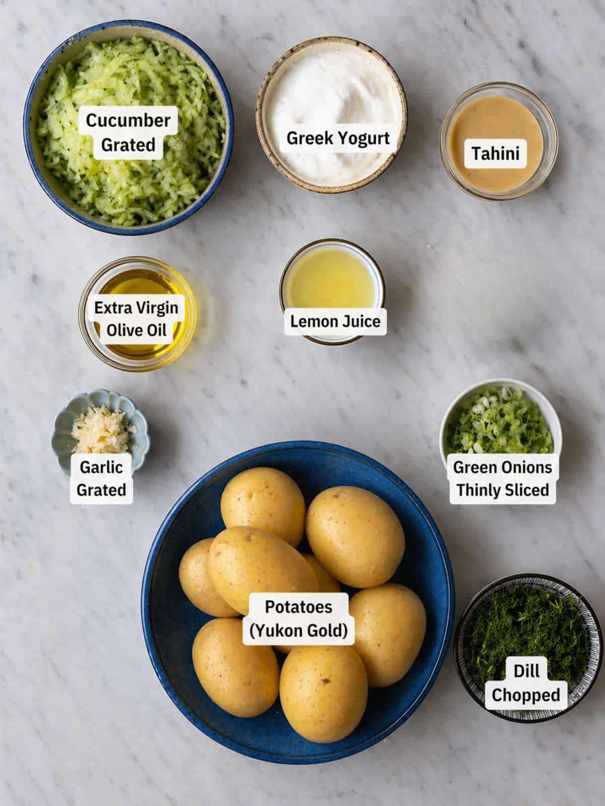 Ingredients for roasted potato salad on marble table in natural window light.