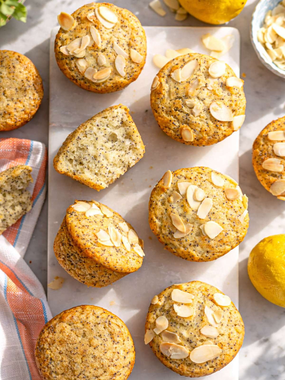 Lemon poppy seed muffins on marble table with soft crumb and golden tops.