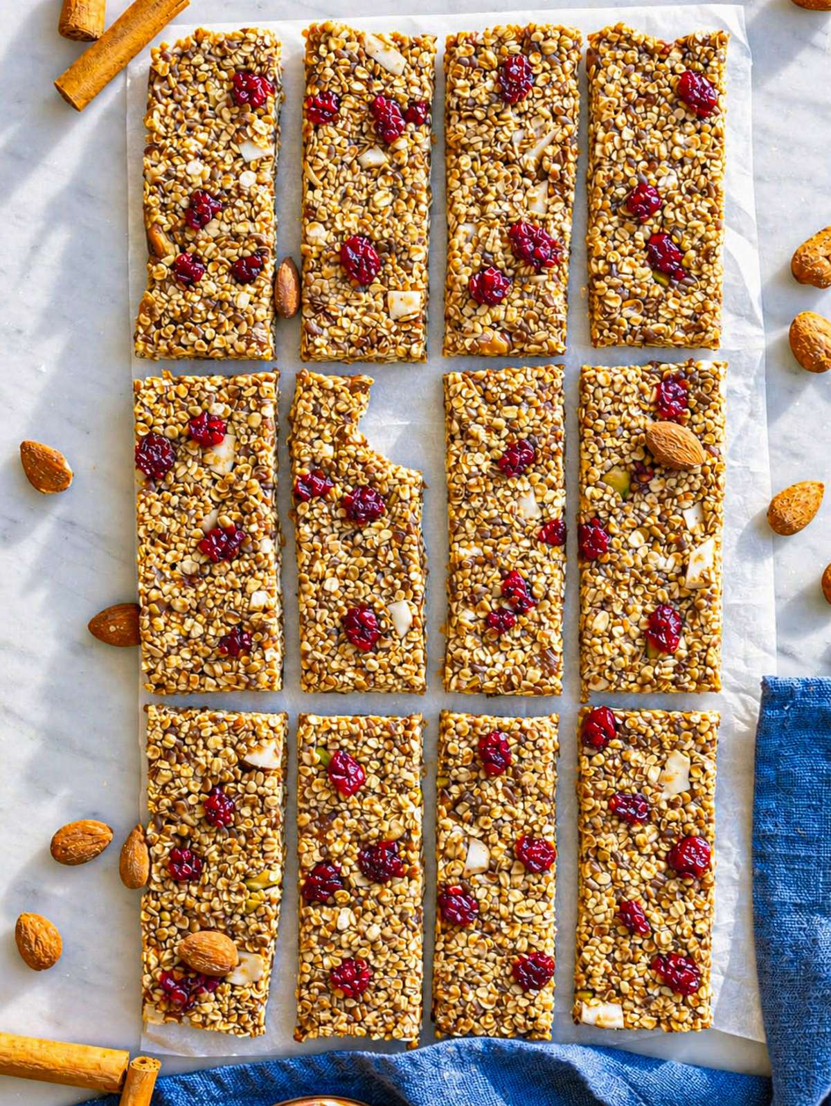 No bake oat bars arranged in rows on parchment paper with almonds and cinnamon sticks.