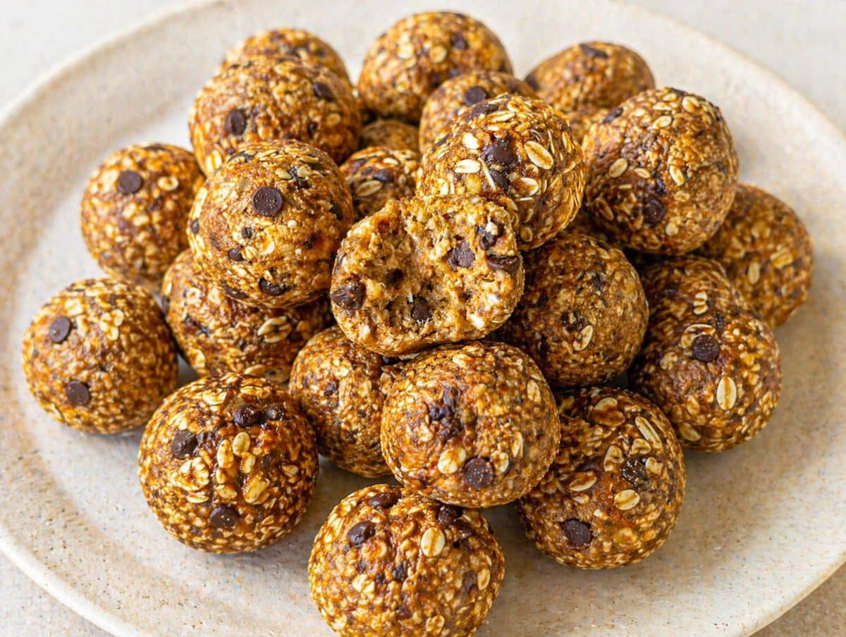 Plate of banana oat energy balls with chocolate chips, one ball cut open to show texture.