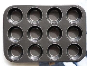 Step 1 Greased muffin pan on marble surface ready for baking.