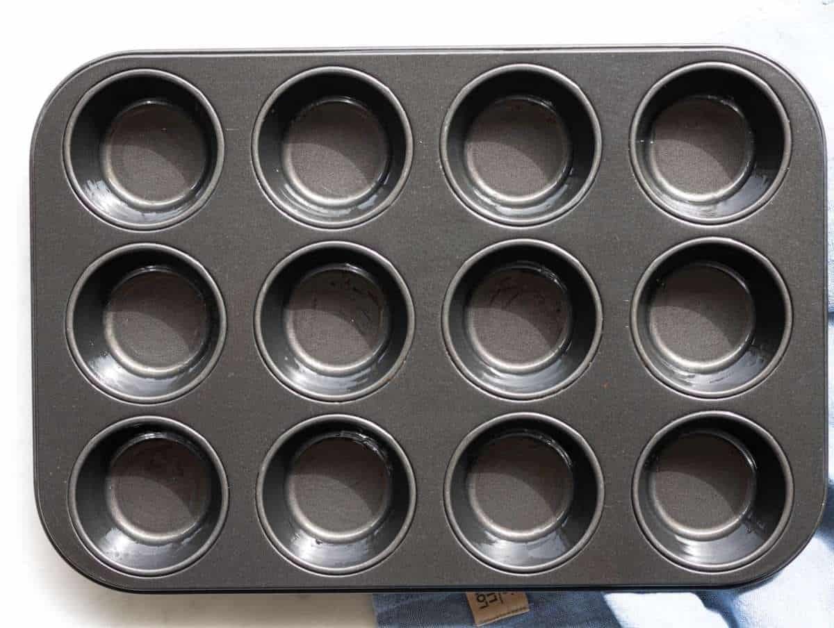 Step 1 Greased muffin pan on marble surface ready for baking.