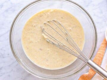 Step 1 Mashed bananas with yogurt and egg in bowl near window light on marble surface.