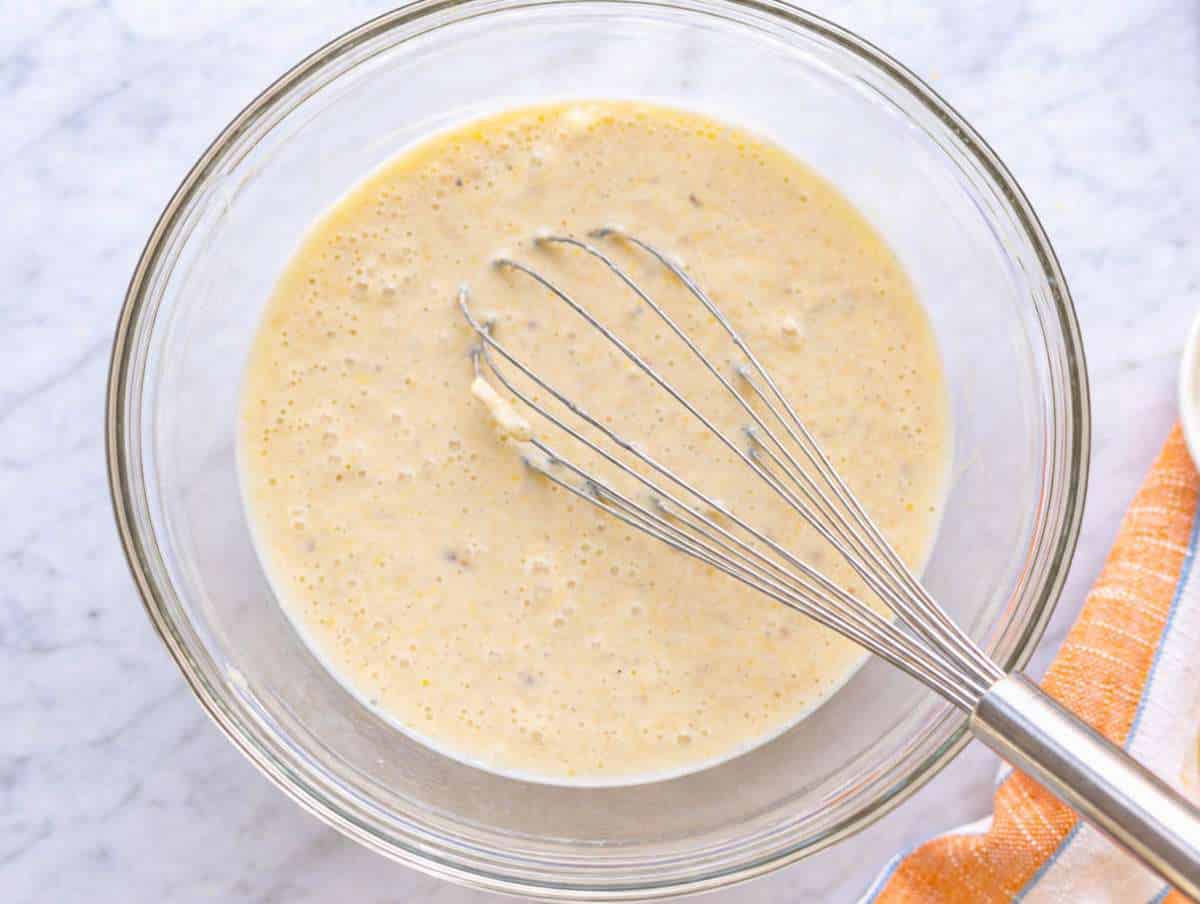 Step 1 Mashed bananas with yogurt and egg in bowl near window light on marble surface.