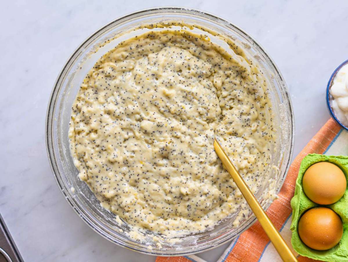 Step 2 Adding flour and dry ingredients into bowl with batter on marble surface.