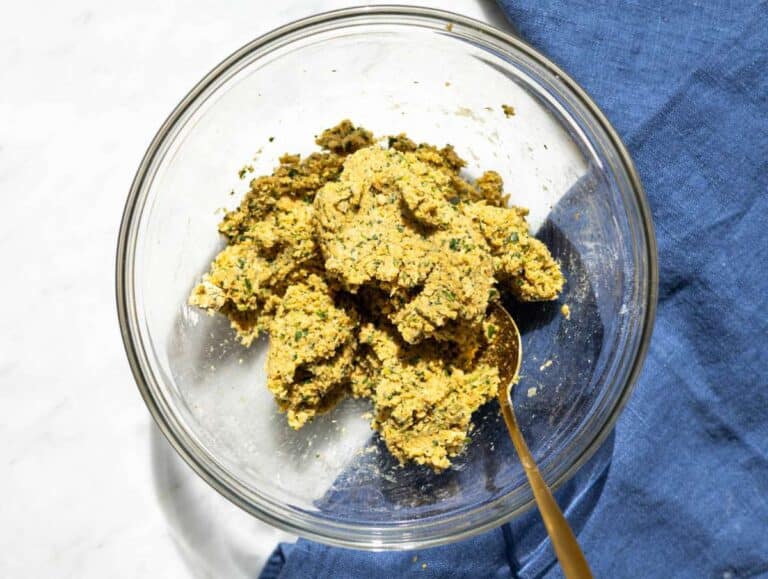 Step 2 Falafel mixture in bowl with flour added, thick dough being mixed with spoon.