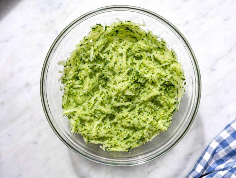 Step 2 Grated cucumber being squeezed by hand to remove excess moisture.
