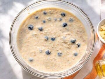 Step 2 Oat mixture with blueberries being gently folded in bowl with natural light.