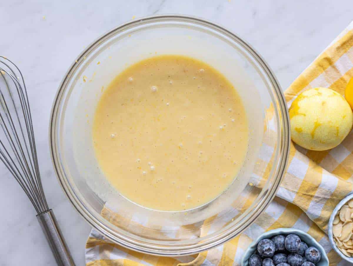 Step 2 Sugar, lemon zest, greek yogurt, and egg mixed in a bowl on a marble surface.