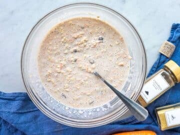 Step 3 Oats fully mixed into wet ingredients, thick mixture in glass bowl on marble.