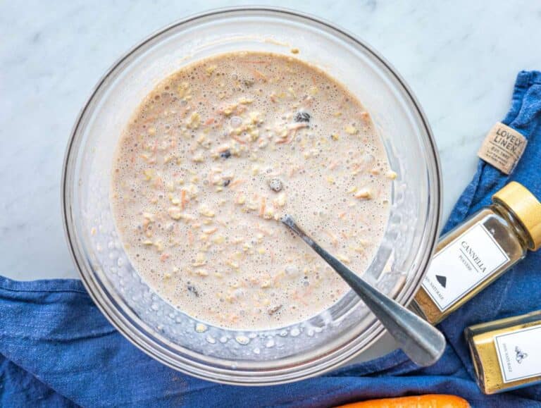 Step 3 Oats fully mixed into wet ingredients, thick mixture in glass bowl on marble.