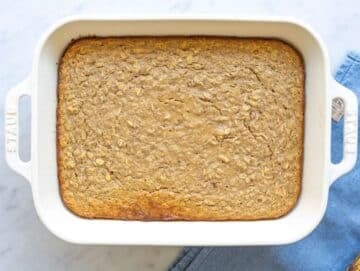 Step 4 Freshly baked oatmeal in pan with golden top resting on marble surface.