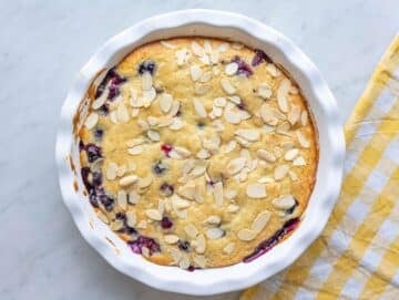 Step 5 Freshly baked blueberry spoon cake cooling in the dish with golden edges.