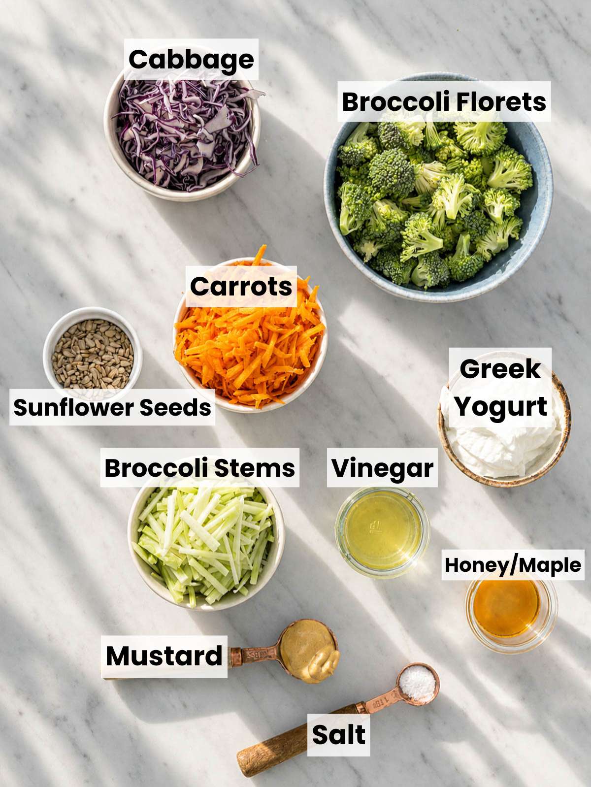 Broccoli, carrots, red cabbage, Greek yogurt, mustard, and sunflower seeds on a marble counter.