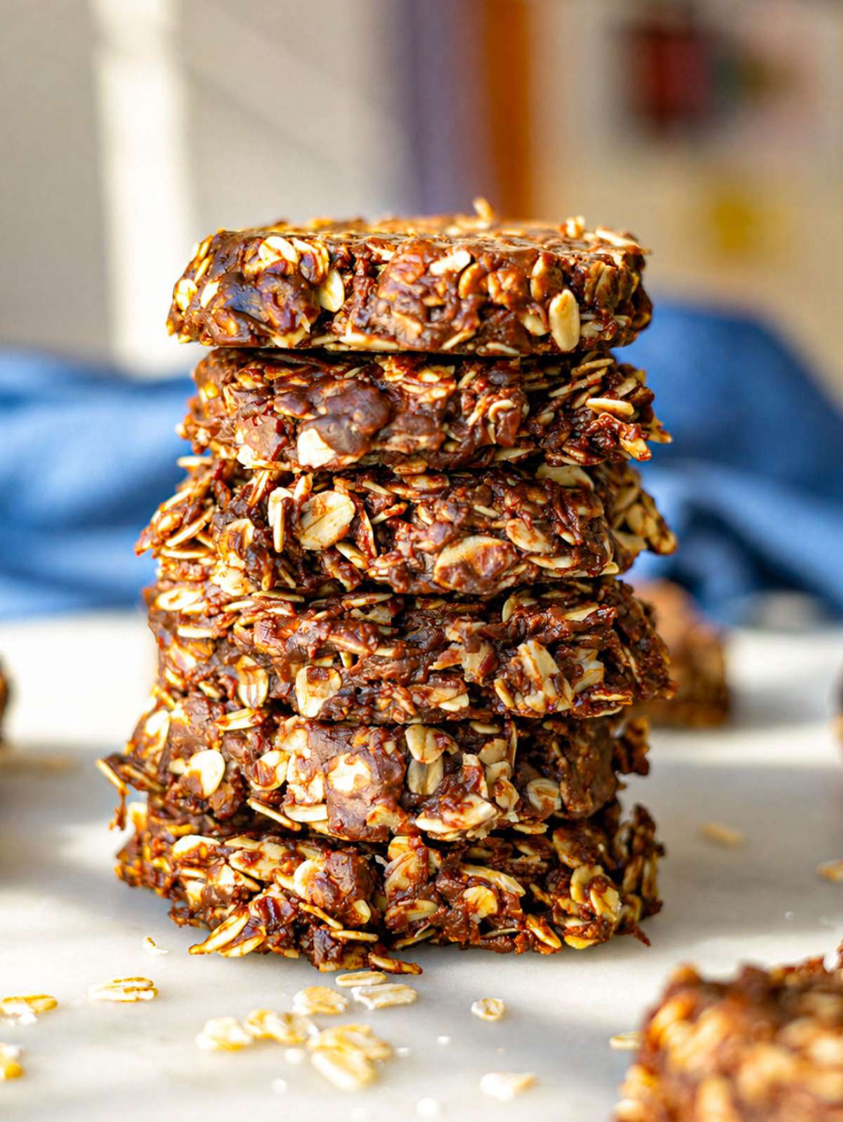 Chocolate oatmeal no bake cookies stacked on a plate near soft window light.