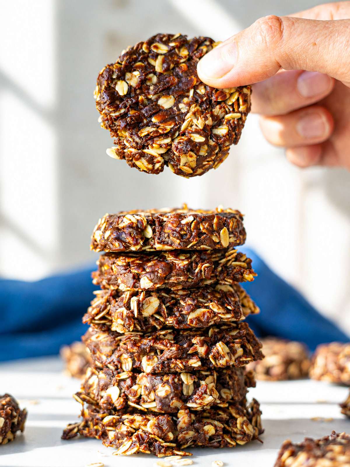 Chocolate oatmeal no bake cookies stacked on a plate near soft window light.
