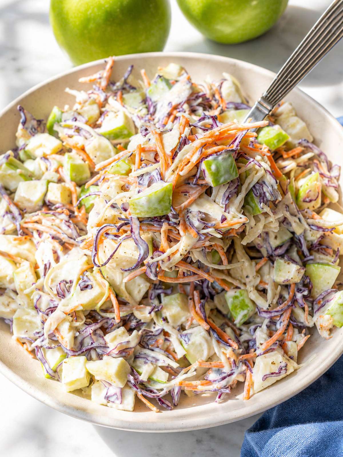 Close-up of apple coleslaw with creamy yogurt dressing and thinly sliced green apples.