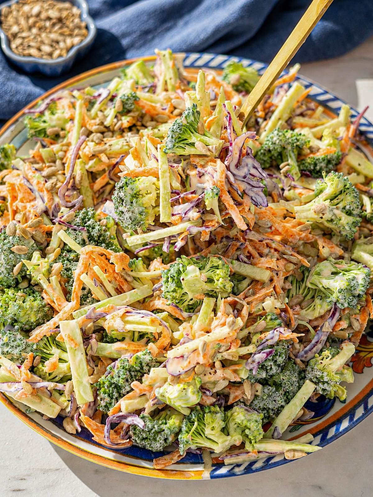 Close-up of broccoli slaw with creamy yogurt dressing and crunchy sunflower seeds in natural light.