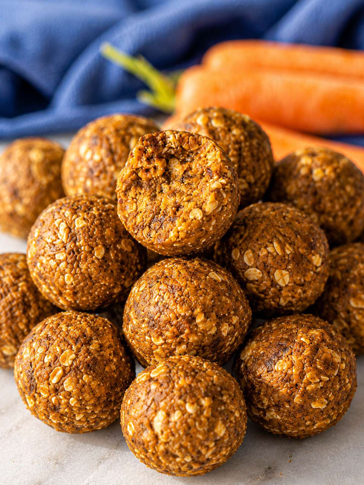 Close-up of carrot cake energy balls with oats on marble surface.