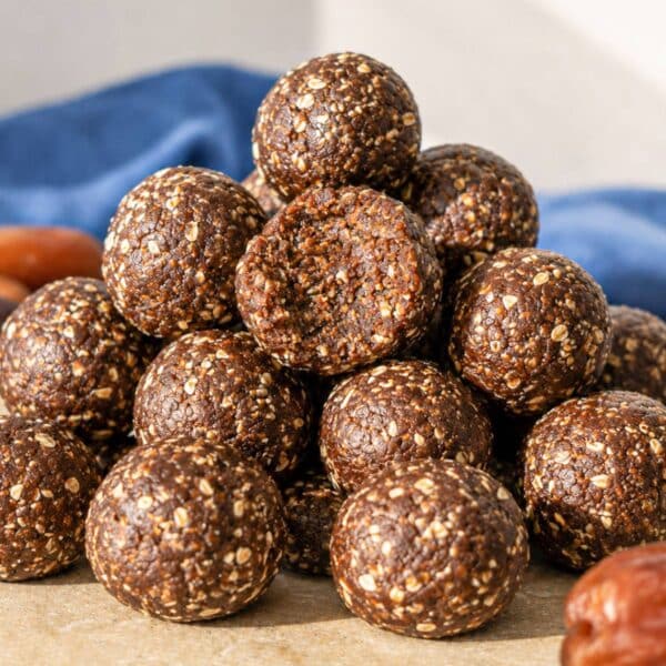 Close-up of chewy chocolate date energy balls stacked on marble surface near natural window light.
