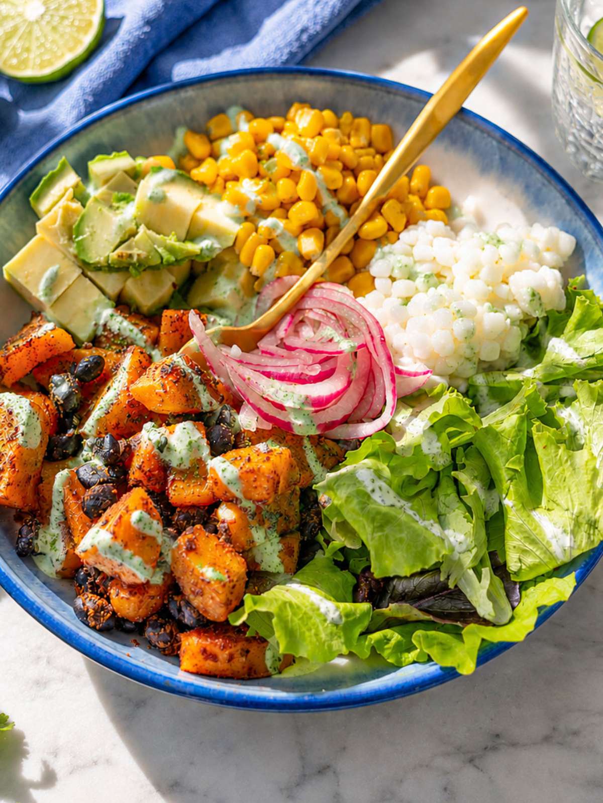 Close-up of roasted sweet potatoes and smoky black beans with creamy dressing.