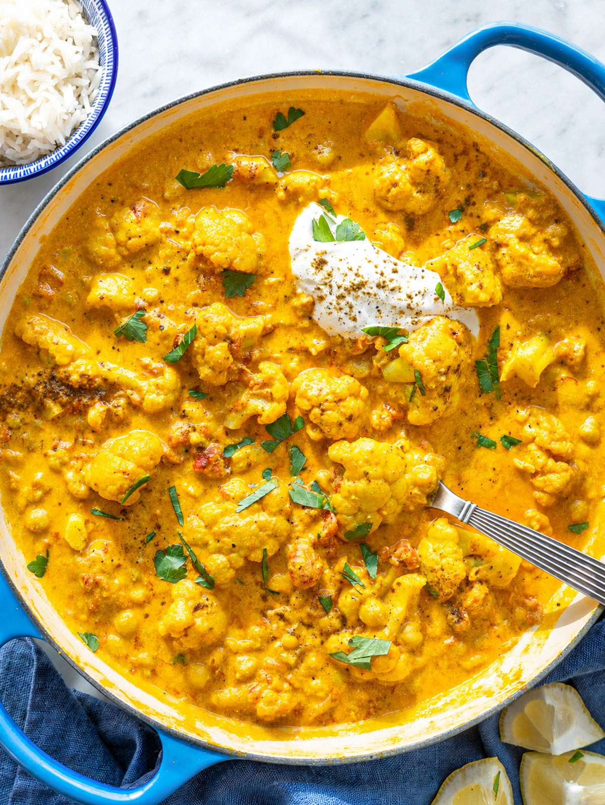 Creamy cauliflower curry with chickpeas and yogurt sauce in large skillet.