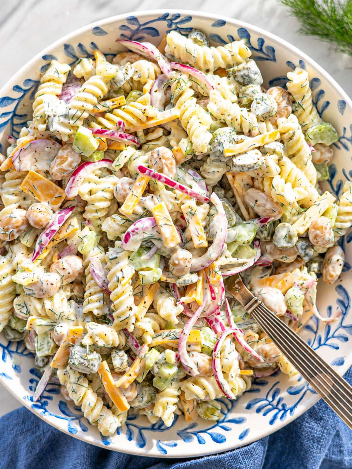 Creamy dill pickle pasta salad served in white bowl with fresh dill and pickles.