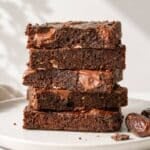 Date brownies stacked on marble with chocolate chips.
