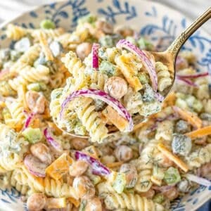 Healthy dill pickle pasta salad in large serving bowl near bright kitchen window.