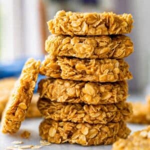 Homemade peanut butter no bake cookies stacked on a marble table near a bright window.