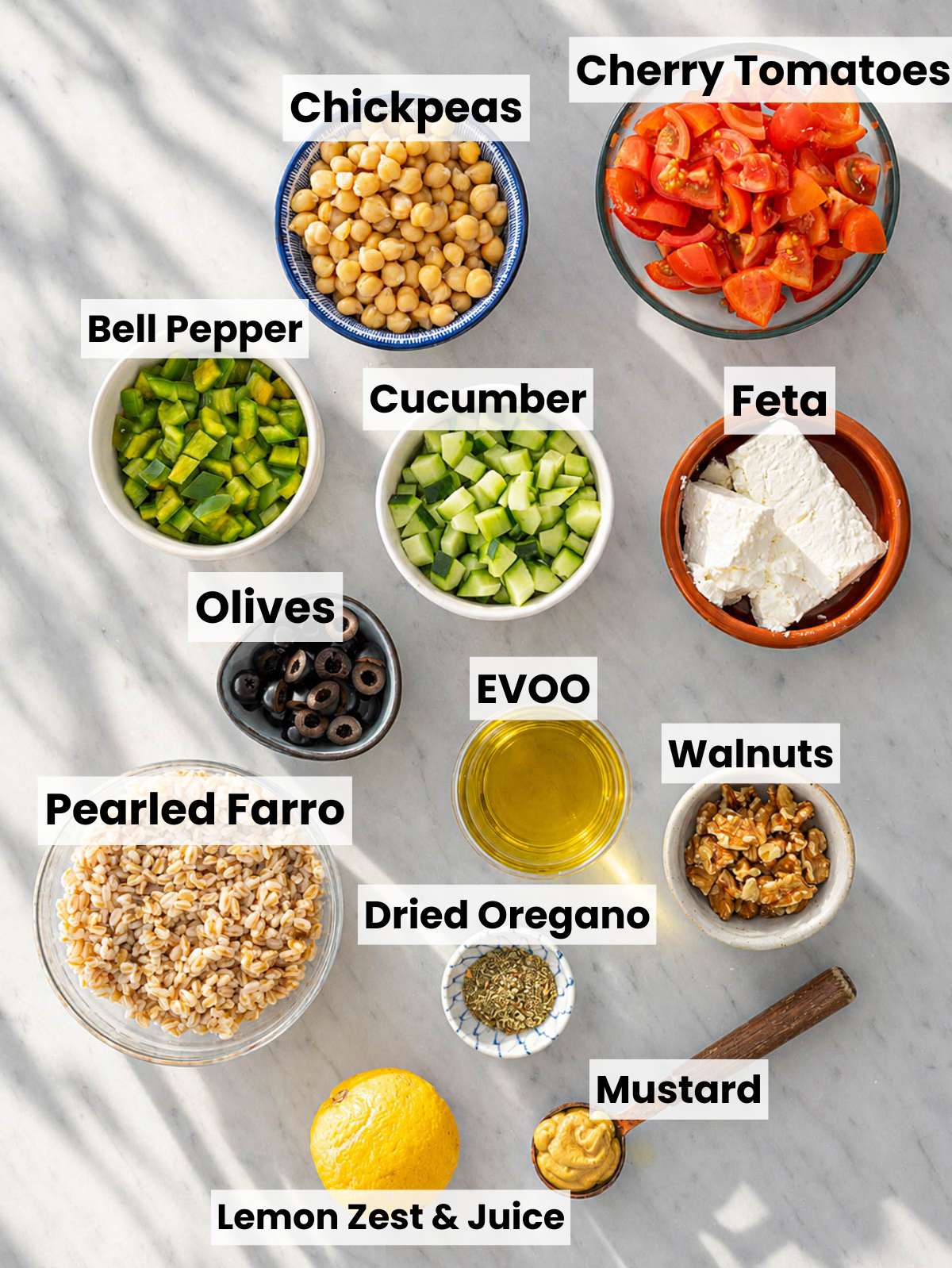 Ingredients for Greek farro salad arranged on marble counter in soft natural window light.