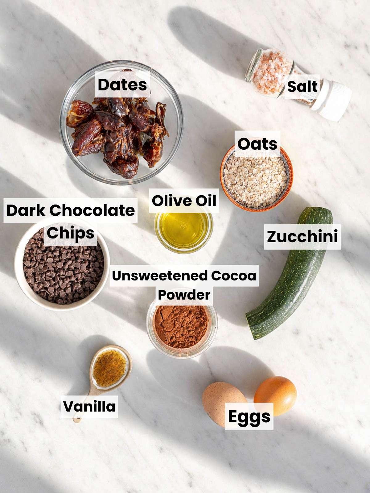 Ingredients for healthy zucchini brownies on a marble countertop.