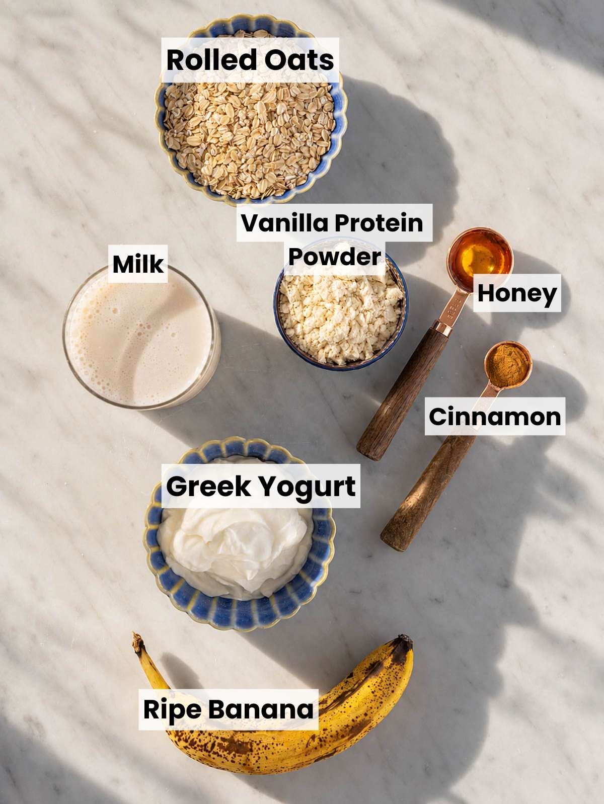 Ingredients for protein overnight oats arranged on a bright marble surface.
