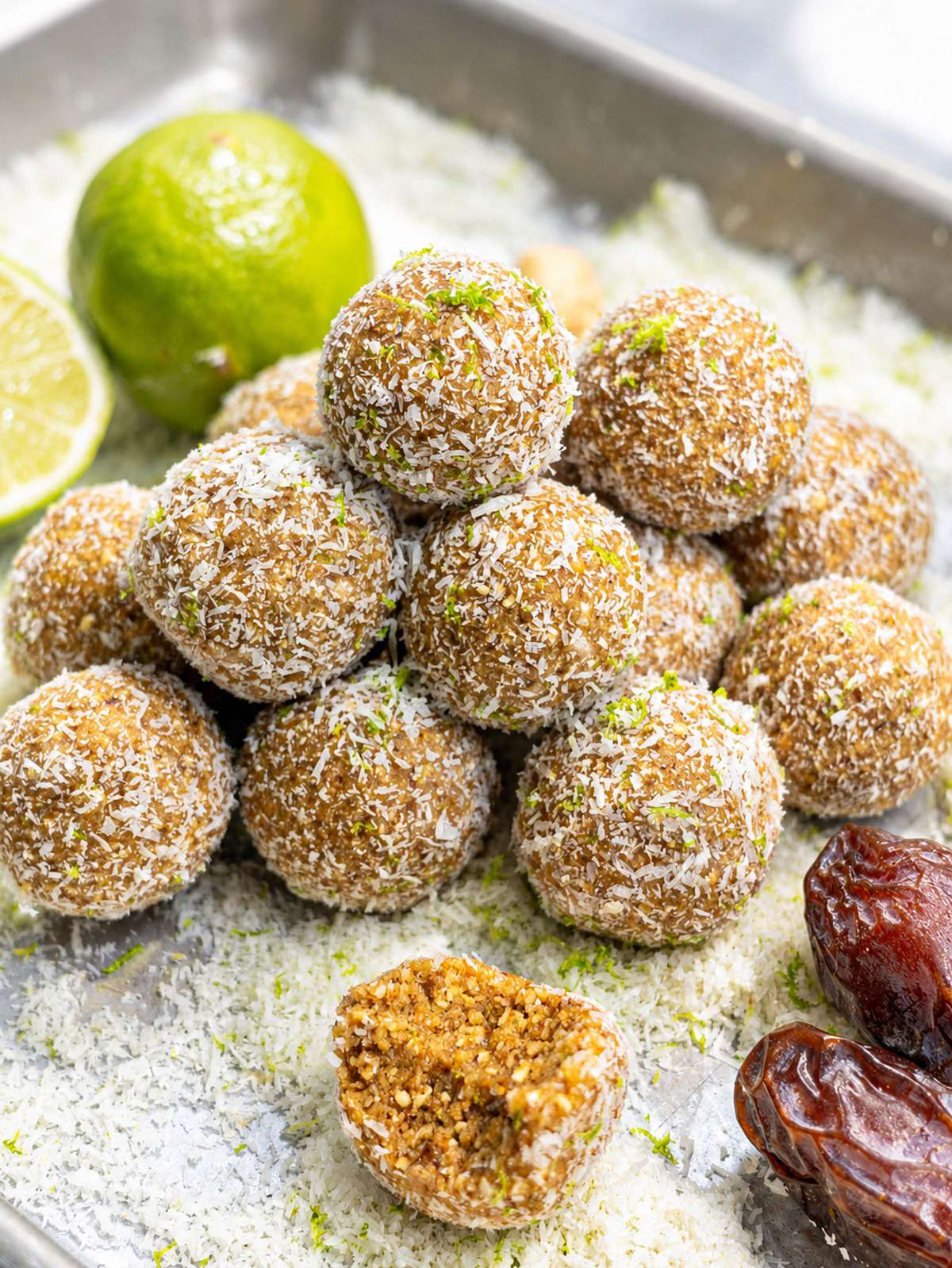 Key lime pie energy balls coated in coconut with lime zest and soft date filling.