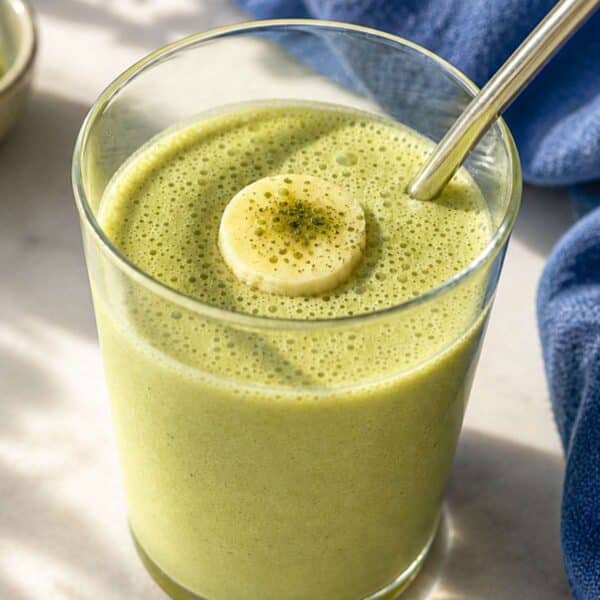 Matcha smoothie in glass with soft light highlighting its smooth, creamy green color.