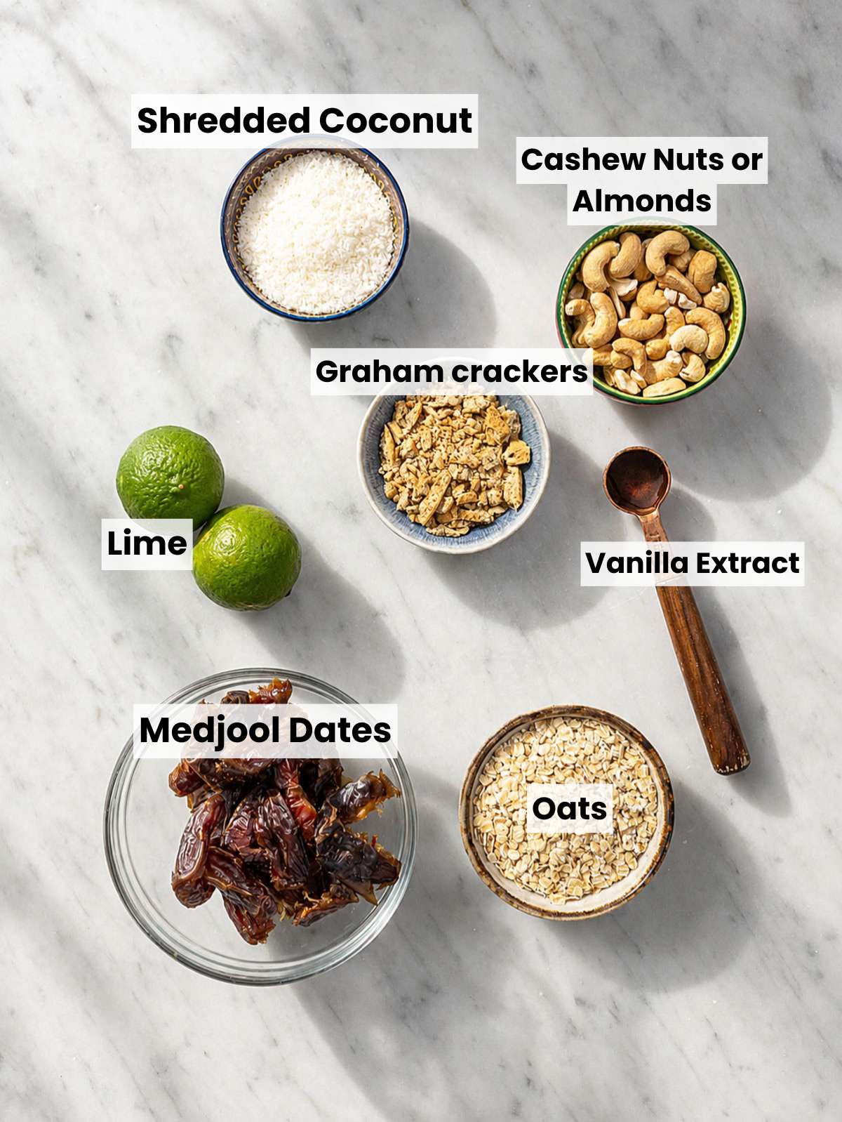 Medjool dates, oats, cashews, coconut, lime, and graham crackers on marble.
