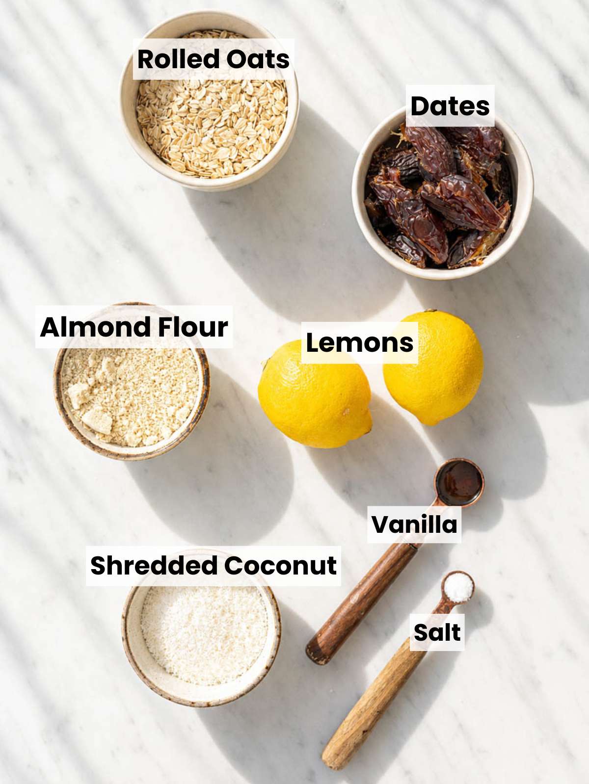 Overhead ingredients for Lemon Energy Balls on white marble counter beside bright window light.