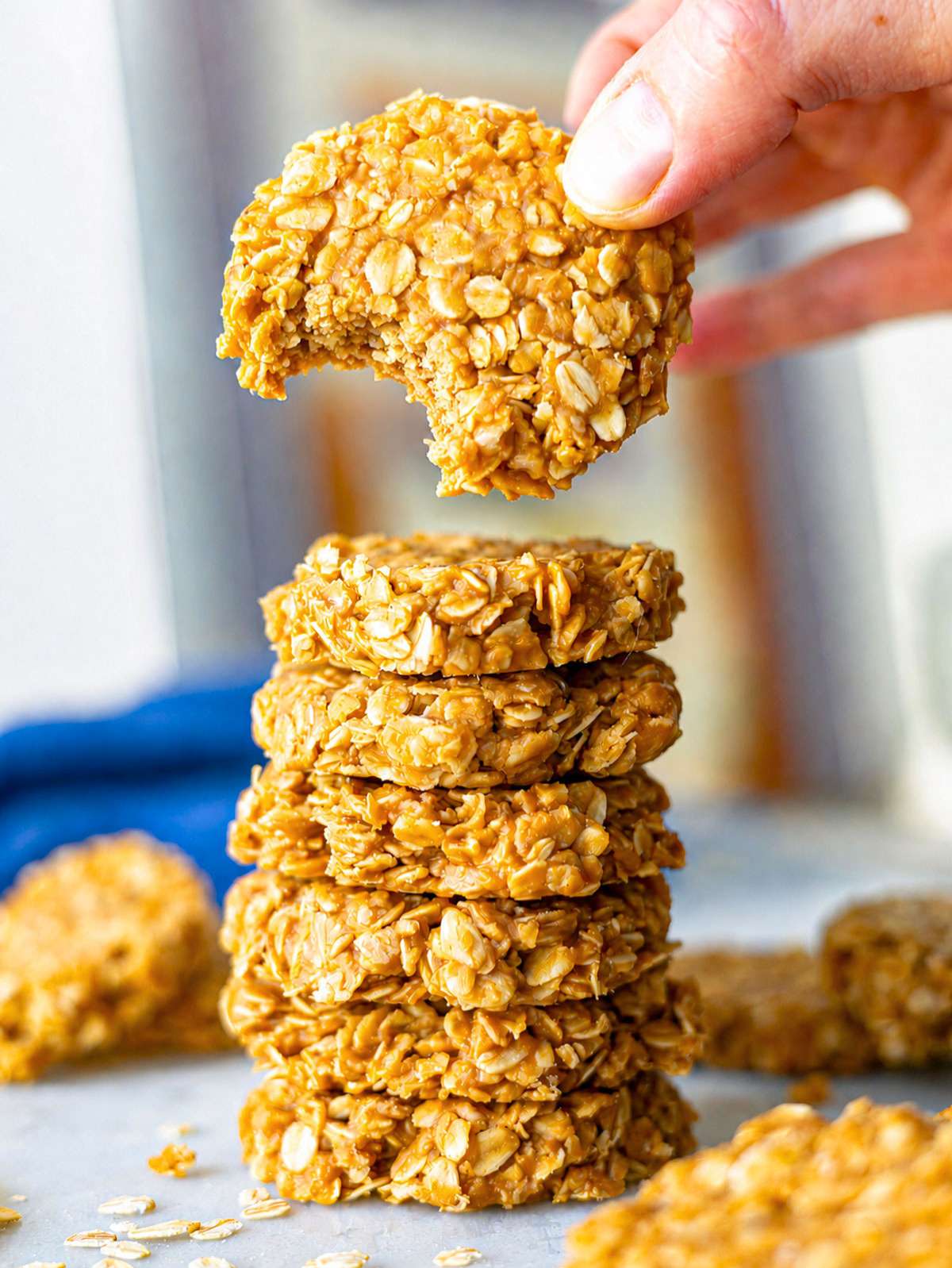 Peanut butter no bake cookies stacked on a marble surface with a female hand.