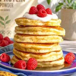 Protein banana pancakes topped with yogurt, raspberries, and maple syrup.