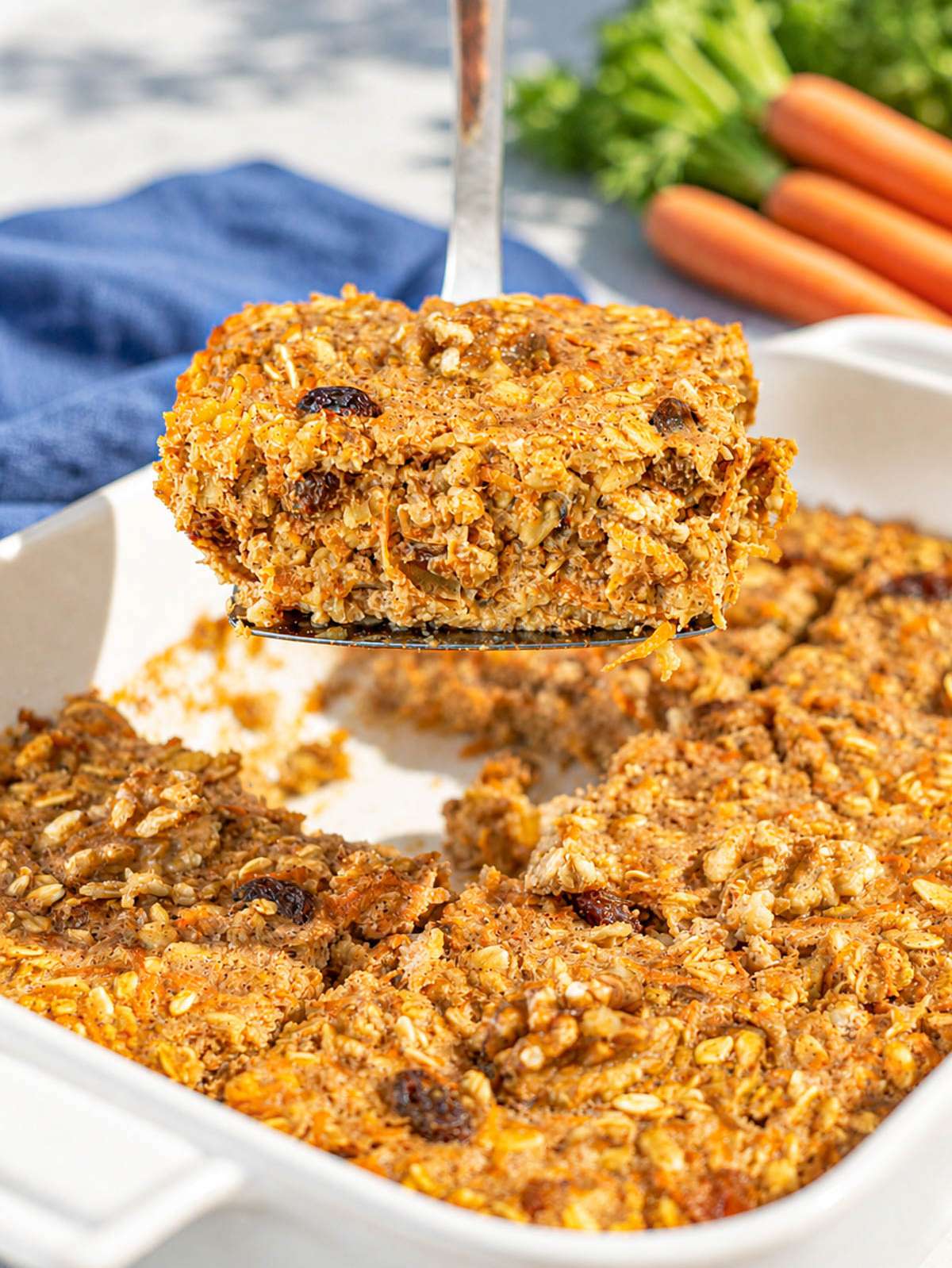 Slice of carrot cake baked oatmeal lifted from dish showing soft, moist texture.